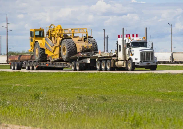 Scraper machine on flatbed trailer